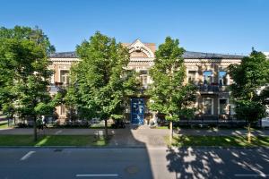 un grand bâtiment avec des arbres en face d'une rue dans l'établissement BEST BALTIC Hotel Druskininkai Central, à Druskininkai