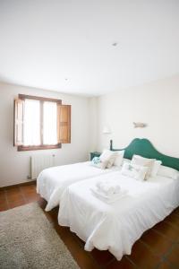 a bedroom with two large white beds and a window at La Fuentona de Ruente in Ruente