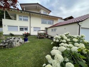 a house with a bush of white flowers in the yard at Holiday apartment Talblick in Unterlenningen