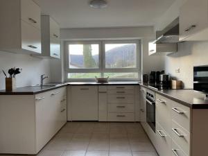 a kitchen with white cabinets and a large window at Holiday apartment Talblick in Unterlenningen