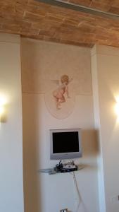 a tv on a wall with a picture of an angel at Una Finestra sul Silenzio Monolocale in Santa Luce