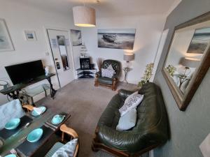 uma sala de estar com um sofá de couro e uma mesa em The Sup Shack Wellington Inn em New Quay