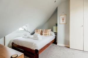 una camera da letto con letto, lenzuola e cuscini bianchi di Knots a Poole