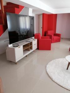 a living room with a large screen tv and red chairs at LA TORRE in Manantiales