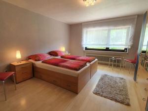 um quarto com uma cama com almofadas vermelhas e uma janela em Holiday apartment in the garden em Eppenbrunn