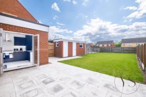 einen Hinterhof mit Rasen und einem Gebäude in der Unterkunft Stylish 3BR Home - Beautiful Garden - Parking in West Bromwich