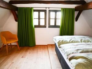 1 dormitorio con cortinas verdes, 1 cama y 1 silla en Holiday home time out in the monument en Lohr