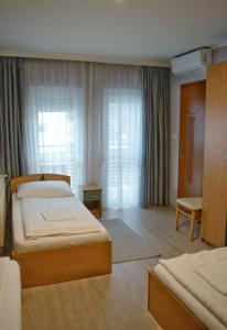 a hotel room with two beds and a window at Alfréd Panzió in Budapest