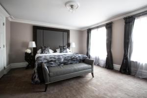 a bedroom with a bed and a chair and windows at One Warwick Park Hotel in Royal Tunbridge Wells