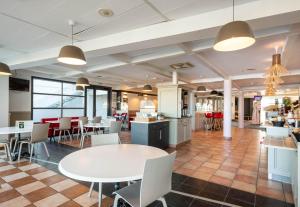 een cafetaria met tafels en stoelen in een gebouw bij B&B HOTEL Calais Terminal Cité Europe 3 étoiles in Coquelles