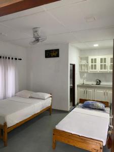 a bedroom with two beds and a kitchen in it at Hikka Lotus Garden in Hikkaduwa