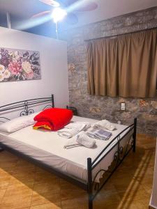 a bed with a red pillow and towels on it at Mani Drosopigi Stonehouse Apartment in Dhrosopiyí