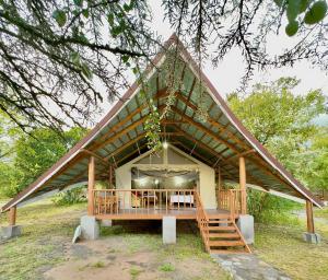 uma casa com telhado de palha, mesa e cadeiras em Mara Empiris Safari Camp em Ololaimutiek