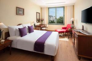 um quarto de hotel com uma grande cama branca com almofadas roxas em Avani Hai Phong Harbour View Hotel em Haiphong
