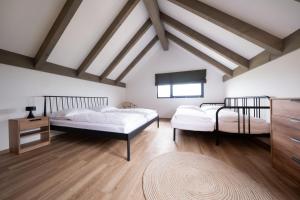 two beds in a room with wooden floors at Apartmány Trojice in Hynčice pod Sušinou
