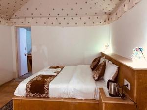Schlafzimmer mit einem Bett mit einem Kopfteil aus Holz in der Unterkunft Royal Luxury Camp Jaisalmer in Jaisalmer