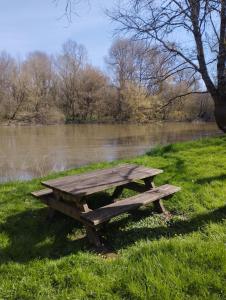 Drewniany stół piknikowy stojący w trawie w pobliżu rzeki w obiekcie Les Ocreries w mieście Saint-Georges-sur-la-Prée +1 zdjęcie