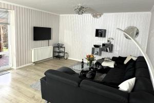 sala de estar con sofá negro y TV en Ferienhaus Wohler 9103 - Fehmarn, en Fehmarn