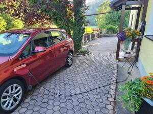 ein rotes Auto, das neben einem Gebäude parkt in der Unterkunft Haus Wiesenttal in Waischenfeld