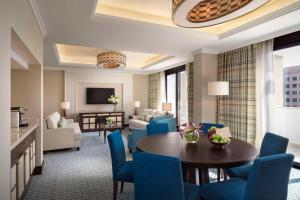 uma sala de estar com uma mesa e cadeiras azuis em Al Najada Doha Hotel by Tivoli em Doha