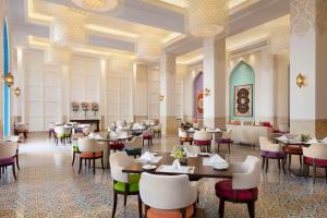 a restaurant with tables and chairs in a room at Al Najada Doha Hotel by Tivoli in Doha