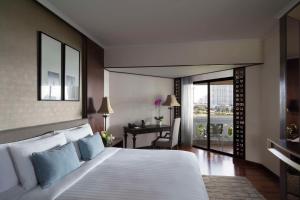 - une chambre avec un grand lit blanc et un bureau dans l'établissement Anantara Riverside Bangkok Resort, à Bangkok