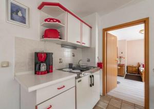 una cucina con armadi bianchi e un apparecchio rosso di Haus Wiesenttal a Waischenfeld