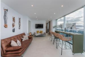 a living room with a couch and a bar with chairs at Gold Suite Canteras by Canarias Homelidays in Las Palmas de Gran Canaria