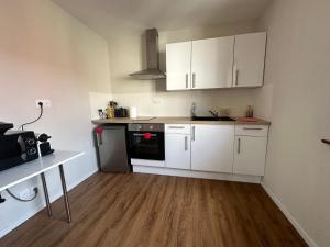 eine kleine Küche mit weißen Schränken und Holzböden in der Unterkunft Charmant appartement 2 pièces in Ostheim