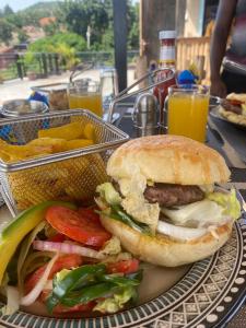 a sandwich on a plate next to a basket of fries at Kitiko residence Hotel in Entebbe