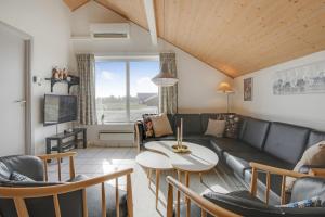 un salon avec un canapé et une table dans l'établissement Cozy holiday house with pool by the sea - SJ940, à Harboør