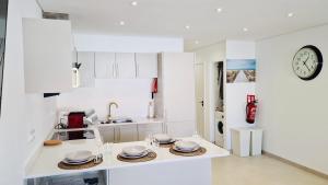 a kitchen with white cabinets and a clock on the wall at Your dream Getaway Awaits in Vale do Lobo in Almancil +19 photos