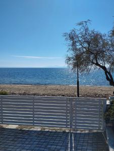un banco junto a una playa con el océano en V.K.Seaside Villa, en Volos