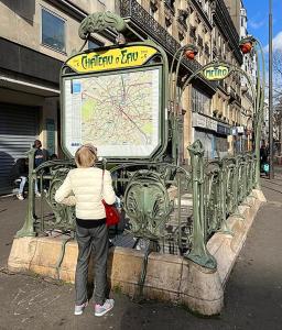 Eine Frau, die eine Karte auf einer Straße ansieht. in der Unterkunft HOTEL DU CHATEAU in Paris