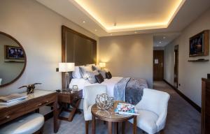 ロイヤル・タンブリッジ・ウェルズにあるOne Warwick Park Hotelのベッド、デスク、椅子が備わるホテルルームです。