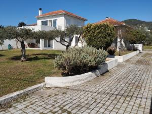 una casa blanca con árboles y una entrada de ladrillo en V.K.Seaside Villa, en Volos