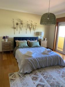 a bedroom with a large bed with a blue headboard at Welcoming house with terrace and garden in Barra de Mira in Areão