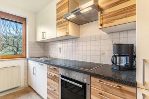 a kitchen with wooden cabinets and a black counter top at Fewo Schwarzwald - Haus Sommerberg in Baiersbronn
