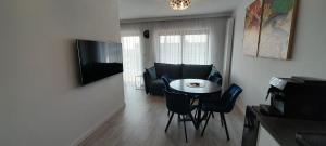 uma sala de estar com uma pequena mesa e cadeiras em Gardenia Seaside Apartament 34 em Dziwnów
