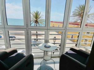 カディスにあるMar Vendaval Grupo AC Gestionのビーチの景色を望む客室で、椅子2脚とテーブルが備わります。