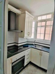 a kitchen with white cabinets and a sink at Mar Vendaval Grupo AC Gestion in Cádiz