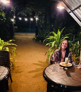 Eine Frau, die an einem Tisch mit einem Teller Essen sitzt. in der Unterkunft Green House Resort in Sigiriya