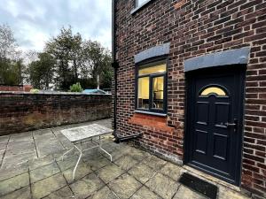 a bench next to a brick building with a door at Tranquil 3 Bed Oasis with Parking in Worsley