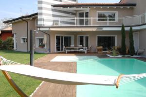 a swimming pool with a hammock in front of a house at Alla casa del Betto in Porto Mantovano