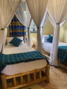 a bedroom with two beds with curtains and a window at Kitiko residence Hotel in Entebbe