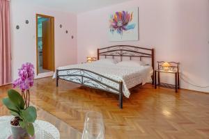 a bedroom with a bed and a wooden floor at House ROSSELLA with cozy apartment and rooms close to the beach in Nerezine