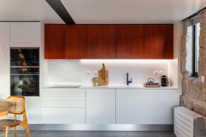 a kitchen with white counters and wooden cabinets at Javardo - Family House - Douro in Penha Longa