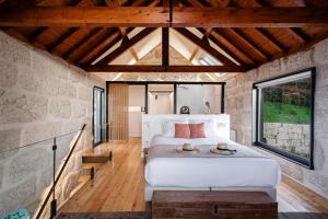 a bedroom with a large bed in a stone wall at Javardo - Family House - Douro in Penha Longa