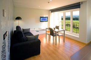 a living room with a couch and a table and a television at Apartamentos Spa Villa Pasiega in Hoznayo