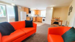 sala de estar con sofá naranja y cocina en Orange Lilly In Stroud With Free Parking en Stroud